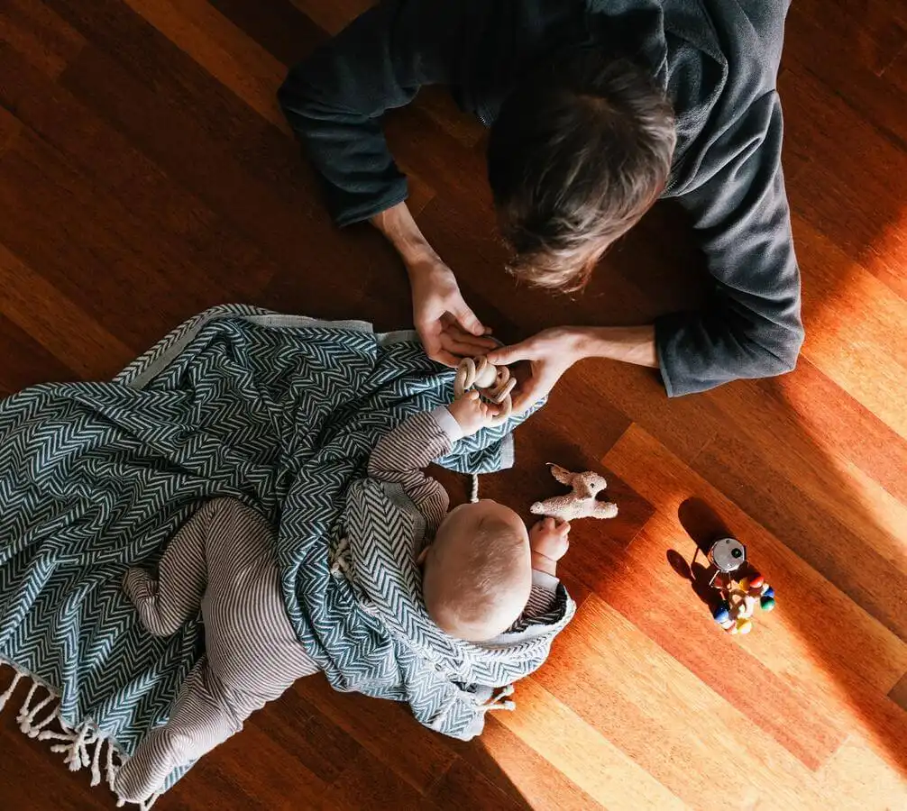 Parent and baby playing on a hardwood floor