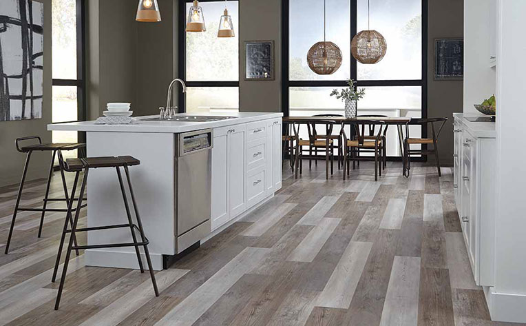 A 2020 themed kitchen with a large with island, stainless steel appliances, and overhead hanging pendant lights.